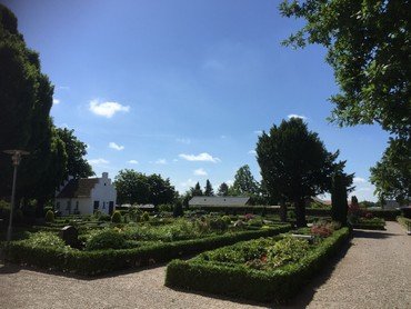 Næsbyhoved Broby Kirkes kirkegård i sol med blå himmel